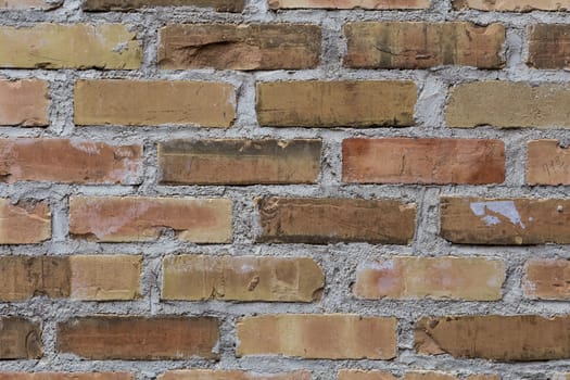 An old brick wall with different colored bricks.
