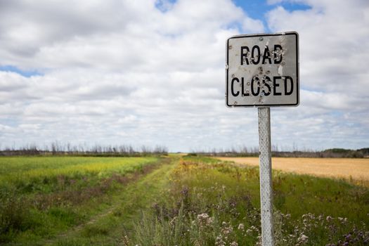 An old road closed sign in rural Saskatchewan with bullet holes in it.
