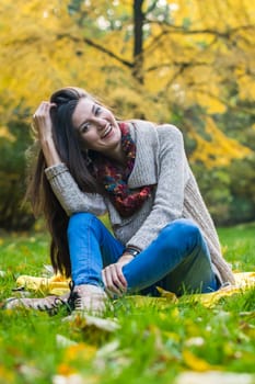 smiling, happy girl sitting on green grass in autumn park