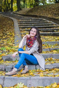 smiling, happy girl sitting on the stairs in the autumn park