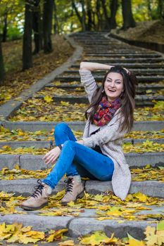 smiling, happy girl sitting on the stairs in the autumn park