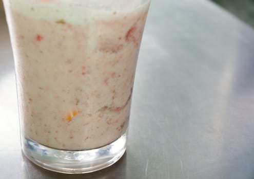COLOR PHOTO OF GLASS WITH STRAWBERRY MILKSHAKE ON STEEL TABLE
