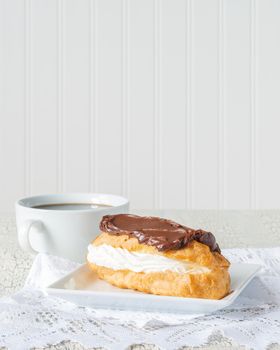 Delicious chocolate eclair served with fresh coffee.