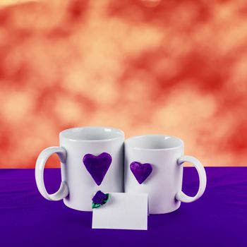 love card with red blur background. blue heart on a white tea cup on a blue fabric