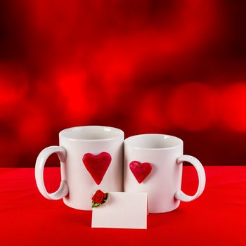 love card with blur background. red heart on a white tea cup on a red fabric