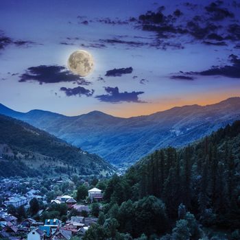 autumn landscape. village on the hillside. forest on the mountain light fall on clearing on mountains at night