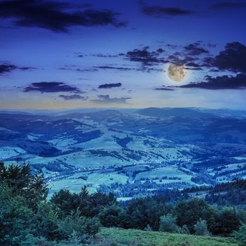 autumn landscape. village on the hillside. forest on the mountain light fall on clearing on mountains at night in moon light