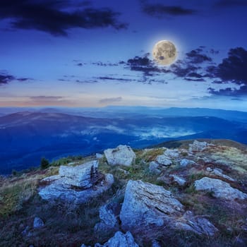 mountain landscape. valley with stones on the hillside. forest on the mountain under the moon light on a clearing at the top of the hill.