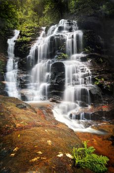 Cascading waterfalls flow over and down rocks as they make their way to the valley floor.  Location - Sylvia Falls, Wentworth Falls Blue Mountains Australia