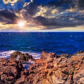 sea ​​wave attacks the boulders and is broken about them at sunset light