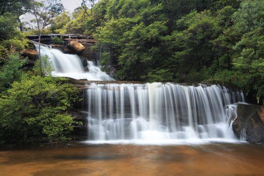 Tranquil waterfalls cascade down rocks before descending over the cliffs.  Location - Wentworth Falls, Blue Mountains, Australia