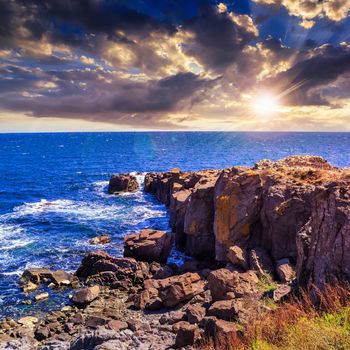 sea ​​wave attacks the boulders and is broken about them at sunset in evening light