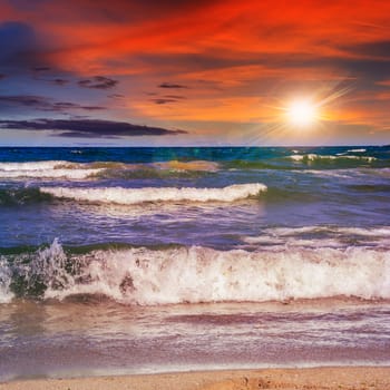 sea wave attacks the sandy beach and break on them at sunset light