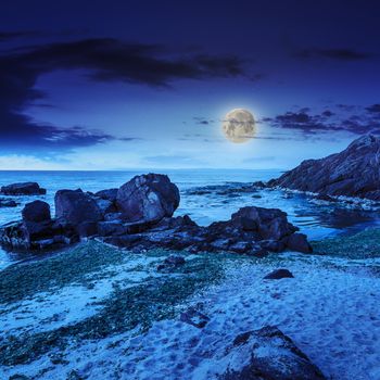 sea wave attacks the sandy beach and break on them at night in moon light