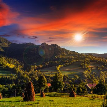 Stack of hay on a green meadow in the mountains in the morning under a blue summer sky at sunset