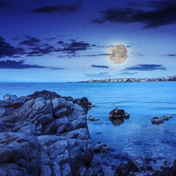 sea coast with boulders near liitle town at night in moon light