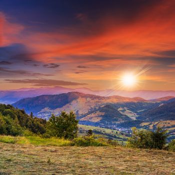 summer landscape. village on the hillside. forest on the mountain light fall on clearing on mountains at sunset