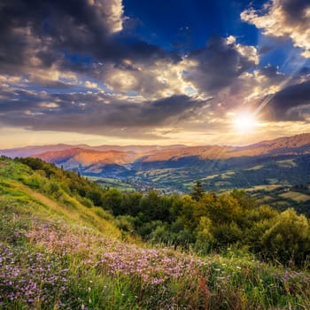 summer landscape. village on the hillside. forest on the mountain light fall on clearing on mountains at sunset