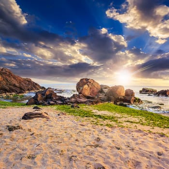 sea wave attacks the boulders and is broken about them at sunset