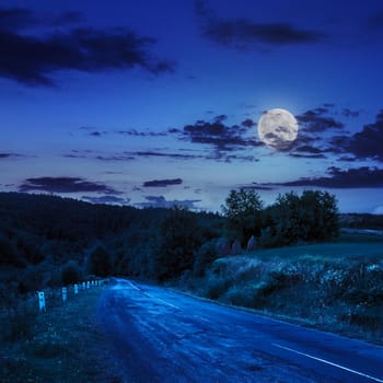 asphalt road going to mountain, passes rural places at night in moon light