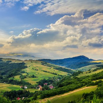 Stack of hay on a green meadow in the mountains in the morning under a blue summer sky