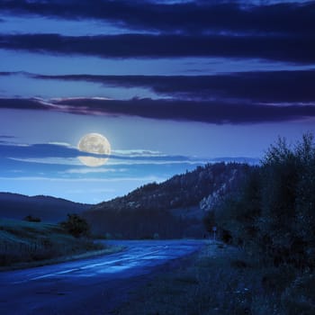 asphalt road going to mountain, passes rural places at night in moon light