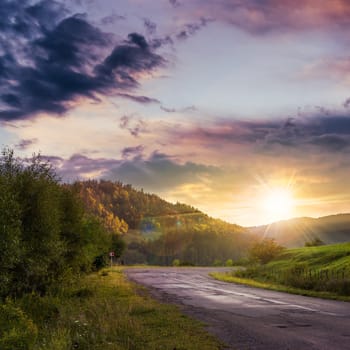 asphalt road going to mountain, passes rural places at sunset