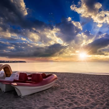 calm sea waves touch  sandy beach with few boats at sunset in evening light