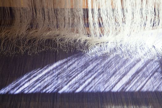 Yarn background, old weaving Loom and thread of yarn. A traditional hand-weaving loom being used to make cloth at home.