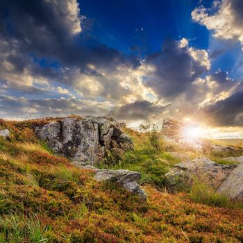 mountain landscape. valley with stones on the hillside under the beam of light falls on a clearing at the top of the hill at sunset.