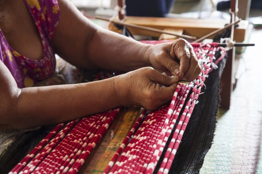 Old asia women demonstrate to procedure of making Thai Silk weaving in small weaving mill