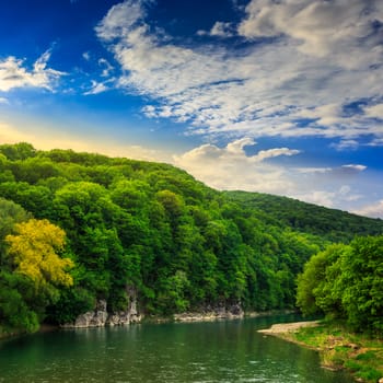 calm river flowing between green mountains on a clear summer morning