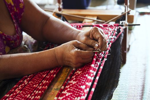 Old asia women demonstrate to procedure of making Thai Silk weaving in small weaving mill