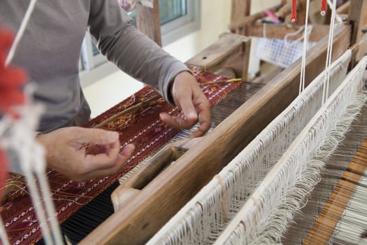 Old asia women demonstrate to procedure of making Thai Silk weaving in small weaving mill