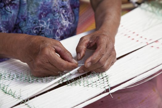 Old asia women demonstrate to procedure of making Thai Silk weaving in small weaving mill