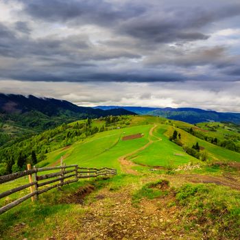 autumn landscape. fence near the meadow path on the hillside. forest in fog on the mountain in morning time