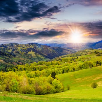 autumn landscape. forest near the meadow on the hillsideon fogy mountain background at sunset