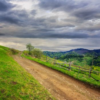 summer landscape. fence near the meadow path on the hillside. forest in fog on the mountain