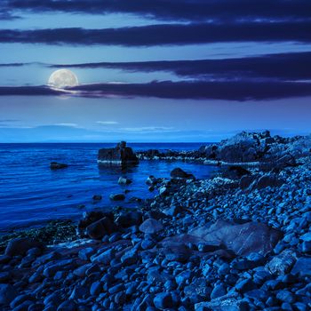 calm sea wave wash  boulders on rocky shore at night in moon light