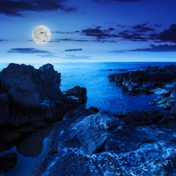 calm sea wave touch giant boulders on rocky shore at night in moon light