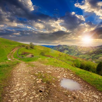 summer landscape. fence near the meadow path on the hillside. forest in fog on the mountain at sunset