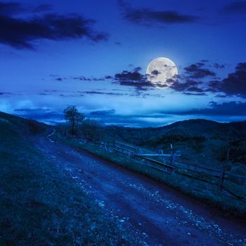 summer landscape. fence near the meadow path on the hillside. forest in fog on the mountain at night in moon light