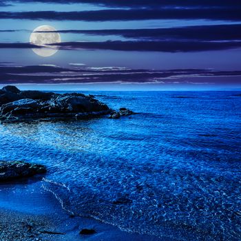 calm sea with some wave on  sandy beach with stones at night