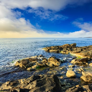 sea wave attacks the boulders and is broken about them