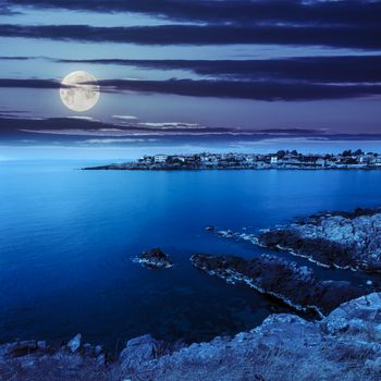 ancient european city on a rocky shore near sea in summer at night in moon light