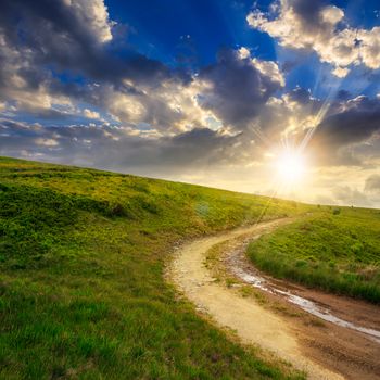 summer landscape. mountain path through the field turns uphill to the sky at sunset