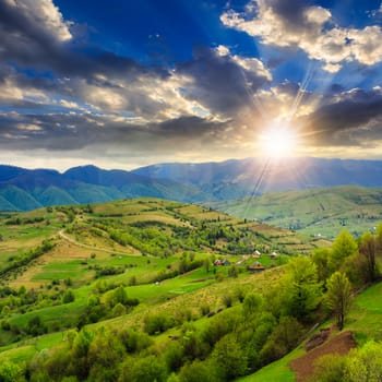 summer landscape. village on the hillside. forest on the mountain light fall on clearing on mountains at sunset