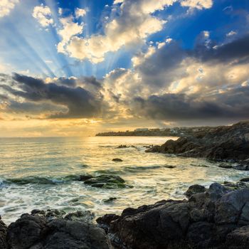 sea wave attacks the boulders and is broken about them at sunrise