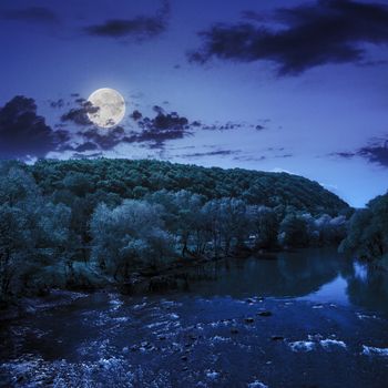 wild river flowing near the camping in  forest at the foot of mountain at night in moon light