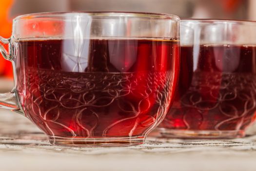 Two full glasses with rooibos tea and bag in soft focus